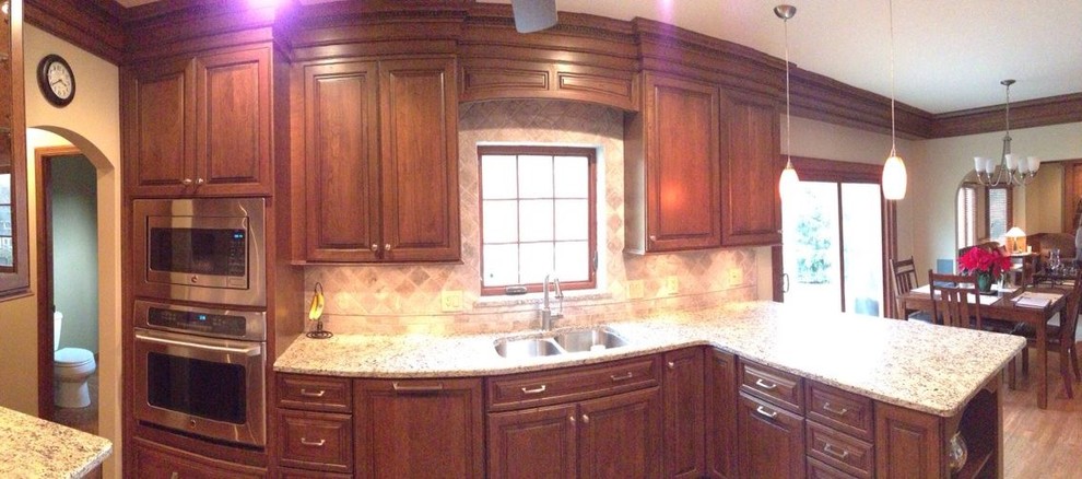 Bild på ett stort vintage kök, med en undermonterad diskho, luckor med upphöjd panel, skåp i mellenmörkt trä, granitbänkskiva, beige stänkskydd, stänkskydd i stenkakel, rostfria vitvaror, mellanmörkt trägolv och en halv köksö