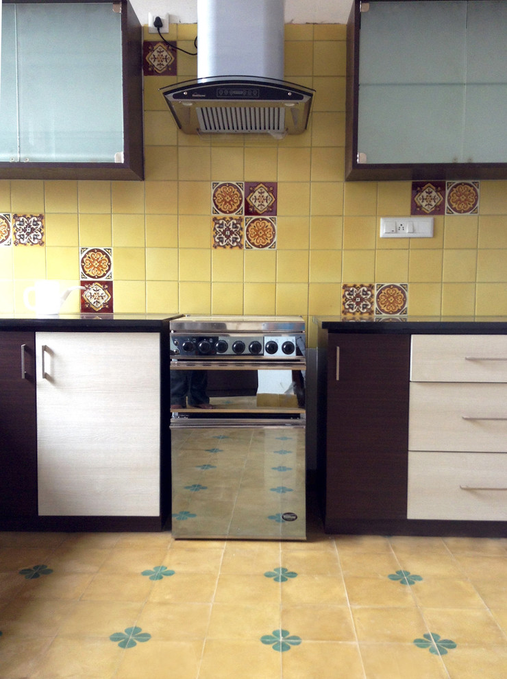 Exempel på ett asiatiskt l-kök, med en enkel diskho, släta luckor, bruna skåp, gult stänkskydd, stänkskydd i keramik, rostfria vitvaror, klinkergolv i terrakotta och en köksö
