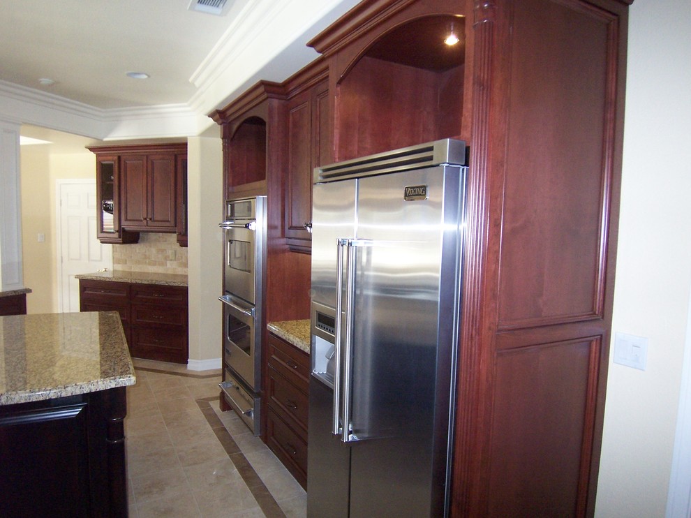 Cette photo montre une cuisine américaine parallèle chic de taille moyenne avec un placard avec porte à panneau surélevé et îlot.