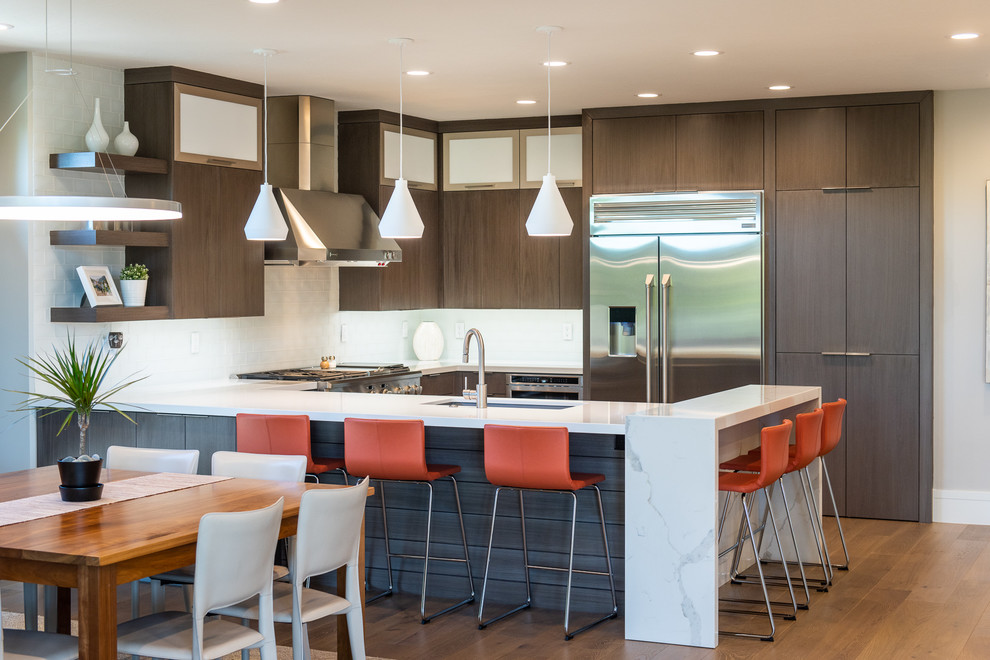Inspiration for a large contemporary u-shaped medium tone wood floor and brown floor eat-in kitchen remodel in Salt Lake City with flat-panel cabinets, an undermount sink, dark wood cabinets, white backsplash, stainless steel appliances, a peninsula and white countertops