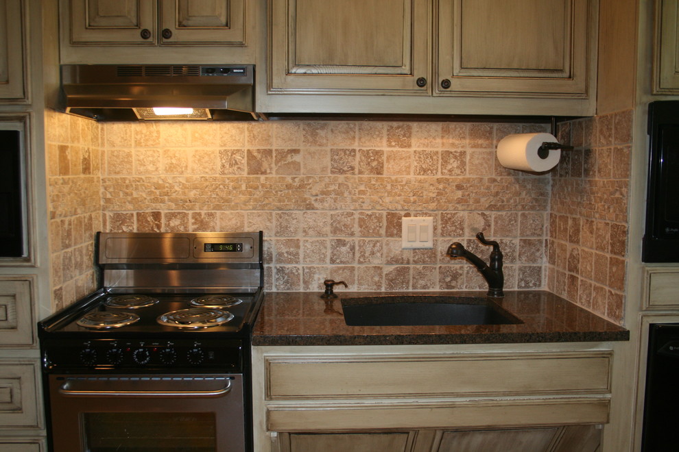 Inredning av ett rustikt mellanstort svart svart kök, med en undermonterad diskho, luckor med upphöjd panel, skåp i ljust trä, granitbänkskiva, beige stänkskydd, stänkskydd i kalk och rostfria vitvaror
