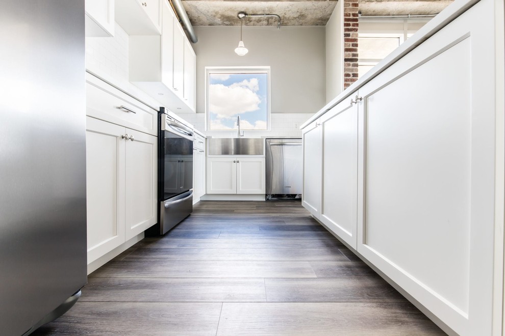 Exempel på ett mellanstort industriellt vit vitt kök, med en rustik diskho, luckor med infälld panel, vita skåp, bänkskiva i kvarts, vitt stänkskydd, stänkskydd i tunnelbanekakel, rostfria vitvaror, mellanmörkt trägolv, en köksö och grått golv