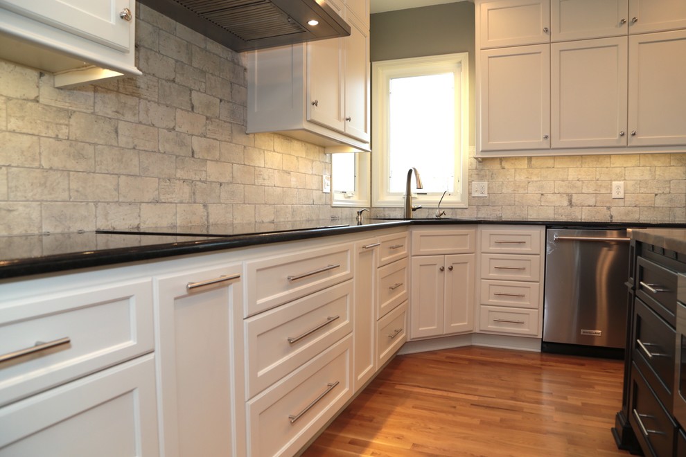 Mid-sized transitional u-shaped light wood floor and brown floor eat-in kitchen photo in Kansas City with an undermount sink, shaker cabinets, white cabinets, granite countertops, white backsplash, brick backsplash, stainless steel appliances and an island