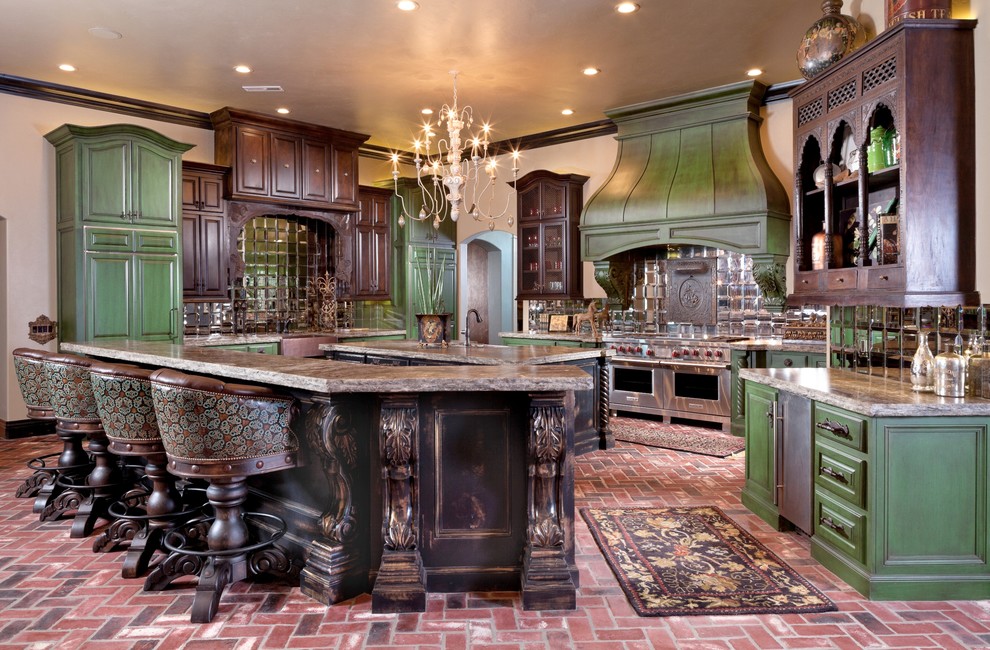 Immagine di un ampio cucina con isola centrale classico con ante verdi, top in granito, paraspruzzi a effetto metallico, paraspruzzi con piastrelle di vetro e pavimento in mattoni