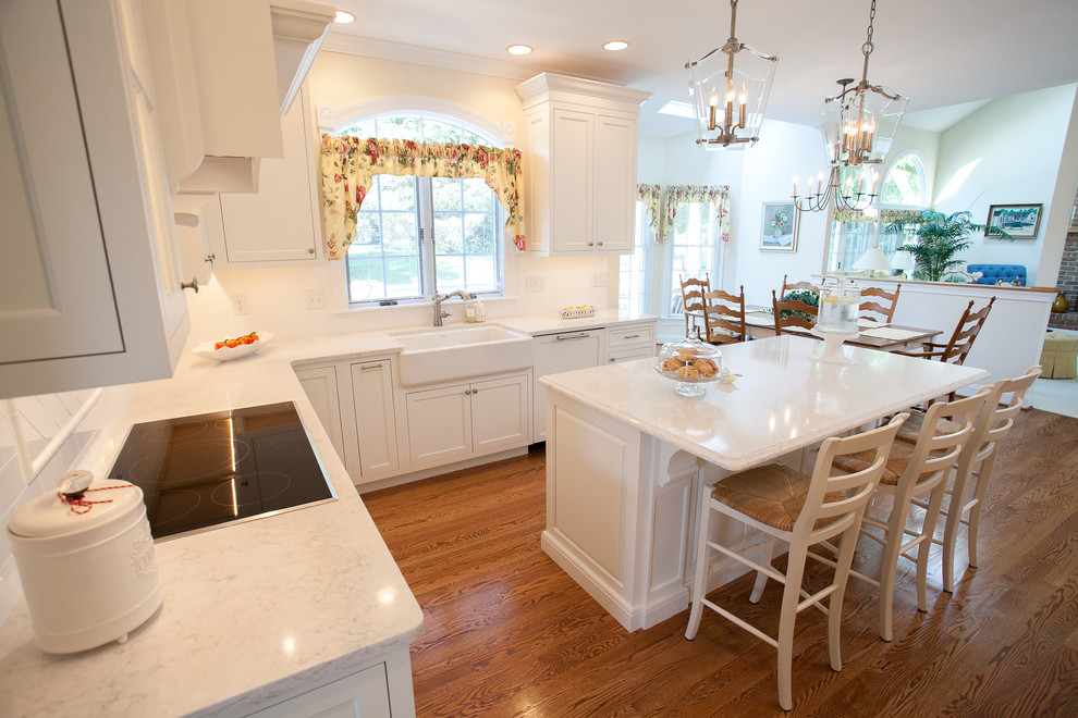 Exempel på ett stort klassiskt vit vitt kök, med en rustik diskho, luckor med infälld panel, vita skåp, bänkskiva i kvarts, vitt stänkskydd, stänkskydd i keramik, integrerade vitvaror, mellanmörkt trägolv, en köksö och brunt golv