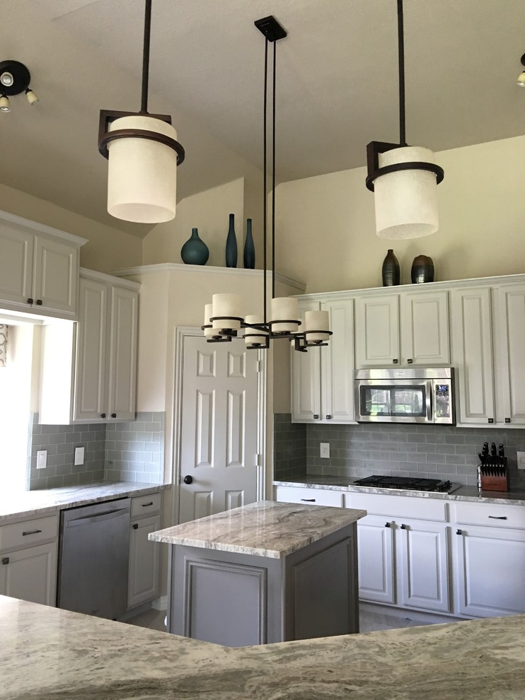 Inspiration for a mid-sized transitional u-shaped porcelain tile and gray floor enclosed kitchen remodel in Dallas with an undermount sink, raised-panel cabinets, white cabinets, marble countertops, gray backsplash, ceramic backsplash, stainless steel appliances and an island