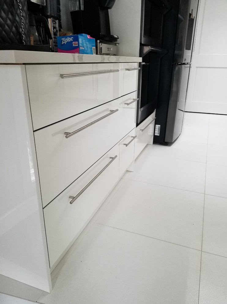 Example of a mid-sized minimalist single-wall porcelain tile and white floor eat-in kitchen design in Detroit with an undermount sink, flat-panel cabinets, white cabinets, quartz countertops, blue backsplash, glass tile backsplash, black appliances, an island and white countertops