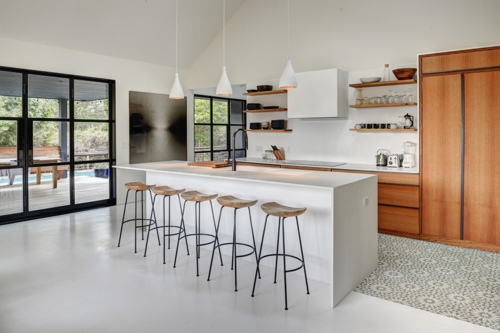 Идея дизайна: кухня в стиле модернизм с плоскими фасадами, фасадами цвета дерева среднего тона, островом, серым полом, белой столешницей и сводчатым потолком