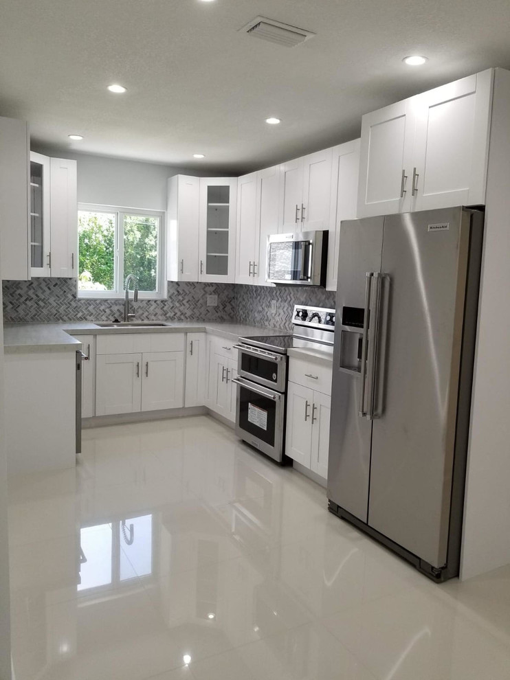 Inspiration for a small contemporary u-shaped open plan kitchen in Miami with a submerged sink, shaker cabinets, white cabinets, granite worktops, grey splashback, mosaic tiled splashback, stainless steel appliances, porcelain flooring, no island, white floors and grey worktops.