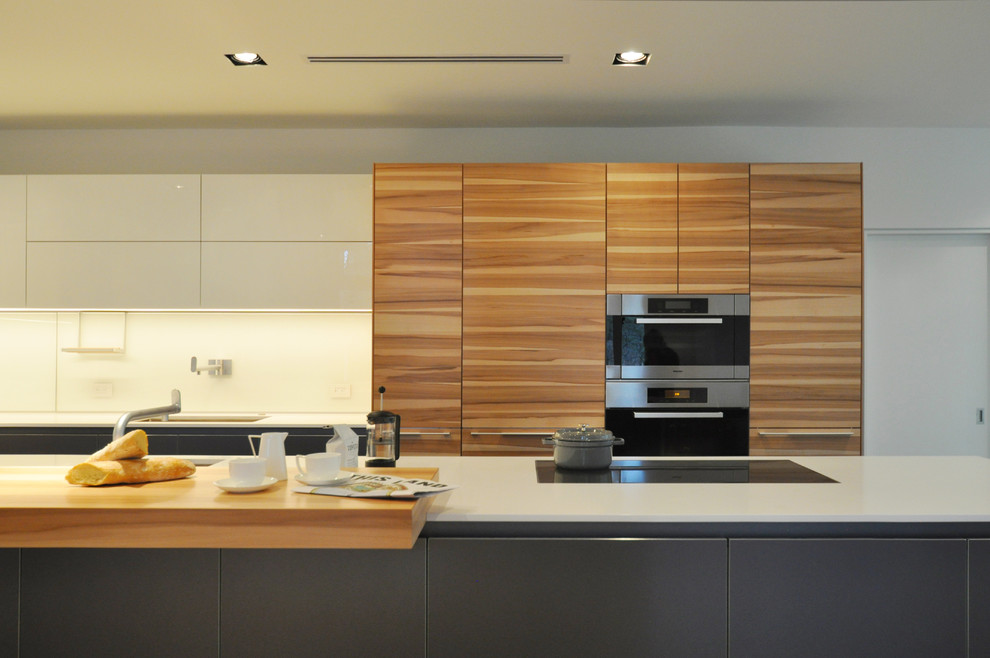 Immagine di una grande cucina minimalista con ante lisce, ante in legno scuro e elettrodomestici in acciaio inossidabile