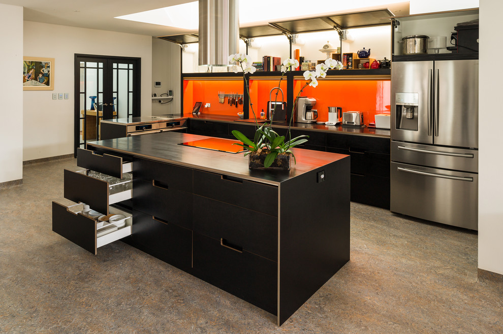 Photo of a large contemporary l-shaped open plan kitchen in Perth with a double-bowl sink, flat-panel cabinets, black cabinets, orange splashback, stainless steel appliances, lino flooring, an island and black worktops.