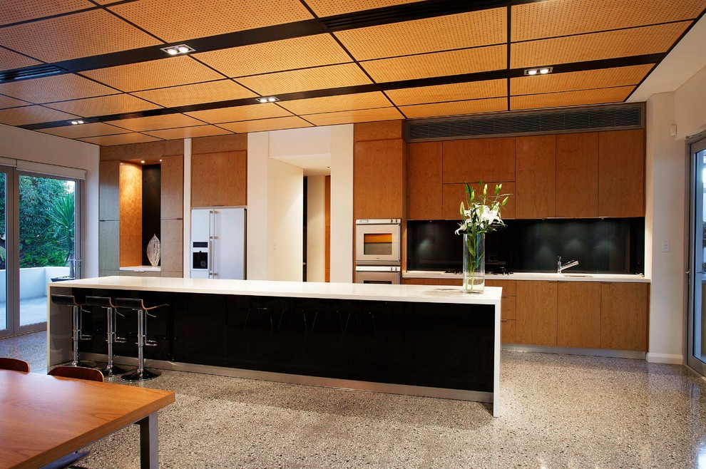 Ispirazione per una cucina design di medie dimensioni con ante in legno chiaro, paraspruzzi nero e pavimento in cemento
