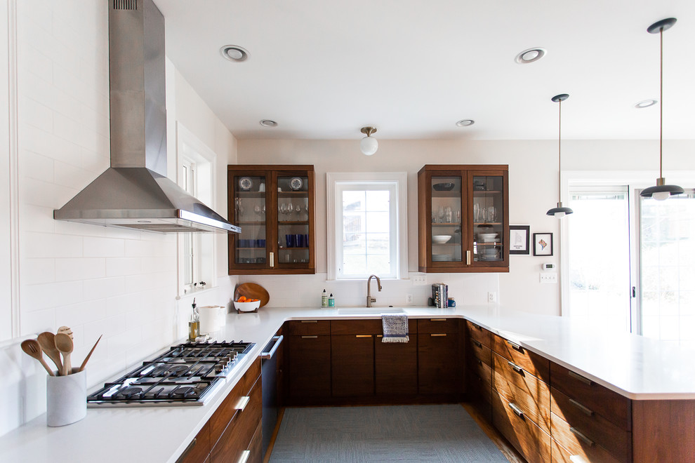 Klassisk inredning av ett stort vit vitt kök, med en undermonterad diskho, luckor med glaspanel, skåp i mörkt trä, bänkskiva i kvarts, vitt stänkskydd, stänkskydd i porslinskakel, rostfria vitvaror, mellanmörkt trägolv och en halv köksö
