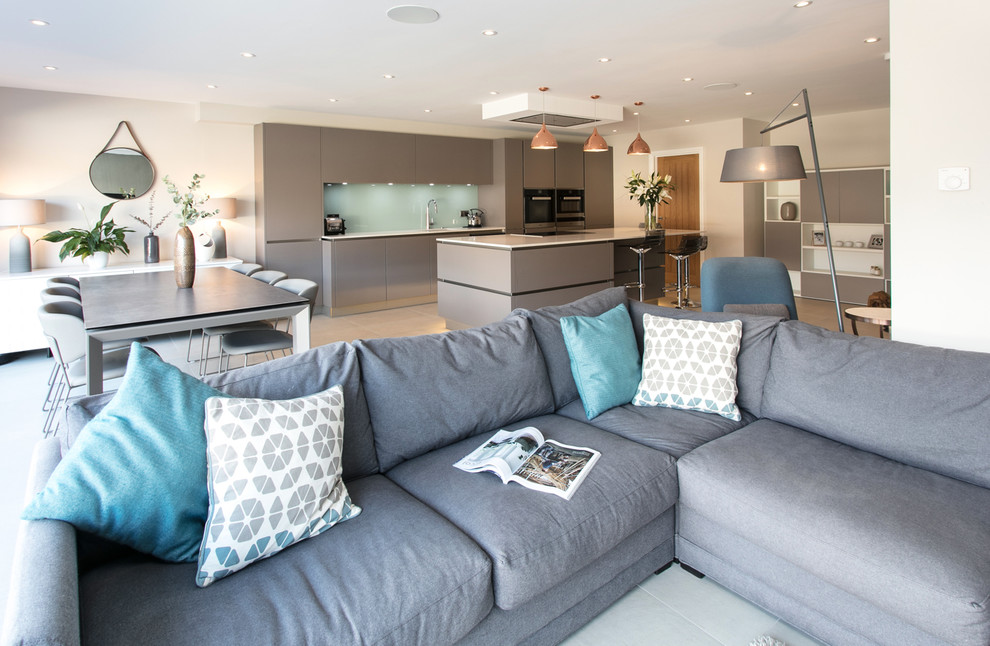 Inspiration for a large contemporary galley open plan kitchen in Surrey with an integrated sink, flat-panel cabinets, grey cabinets, quartz worktops, green splashback, glass sheet splashback, stainless steel appliances, porcelain flooring, an island, grey floors and white worktops.
