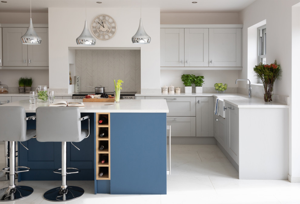 Photo of a traditional l-shaped kitchen in Other with a belfast sink, shaker cabinets, grey cabinets, stainless steel appliances, an island, white floors and white worktops.