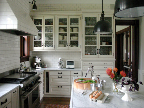 Large elegant u-shaped medium tone wood floor and brown floor kitchen photo in Chicago with a farmhouse sink, raised-panel cabinets, white cabinets, marble countertops, white backsplash, subway tile backsplash, stainless steel appliances, an island and white countertops
