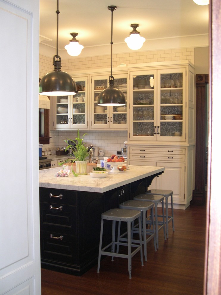 Inredning av ett klassiskt stort vit vitt u-kök, med en rustik diskho, luckor med upphöjd panel, vita skåp, marmorbänkskiva, vitt stänkskydd, stänkskydd i tunnelbanekakel, rostfria vitvaror, mellanmörkt trägolv, en köksö och brunt golv