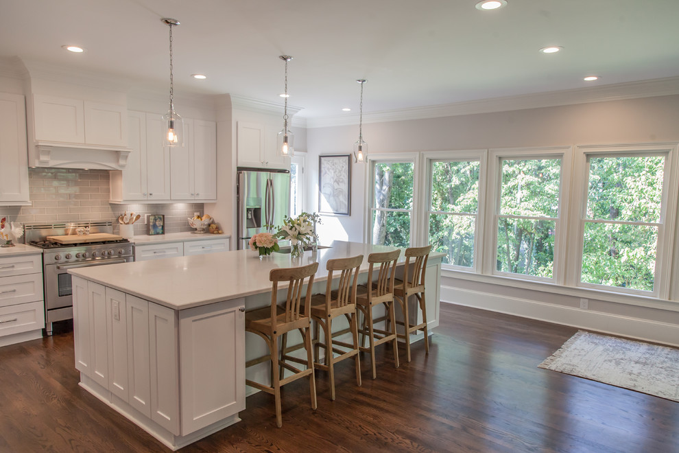 Inspiration for a large timeless single-wall medium tone wood floor and brown floor open concept kitchen remodel in Atlanta with an undermount sink, shaker cabinets, white cabinets, quartzite countertops, gray backsplash, ceramic backsplash, stainless steel appliances and an island