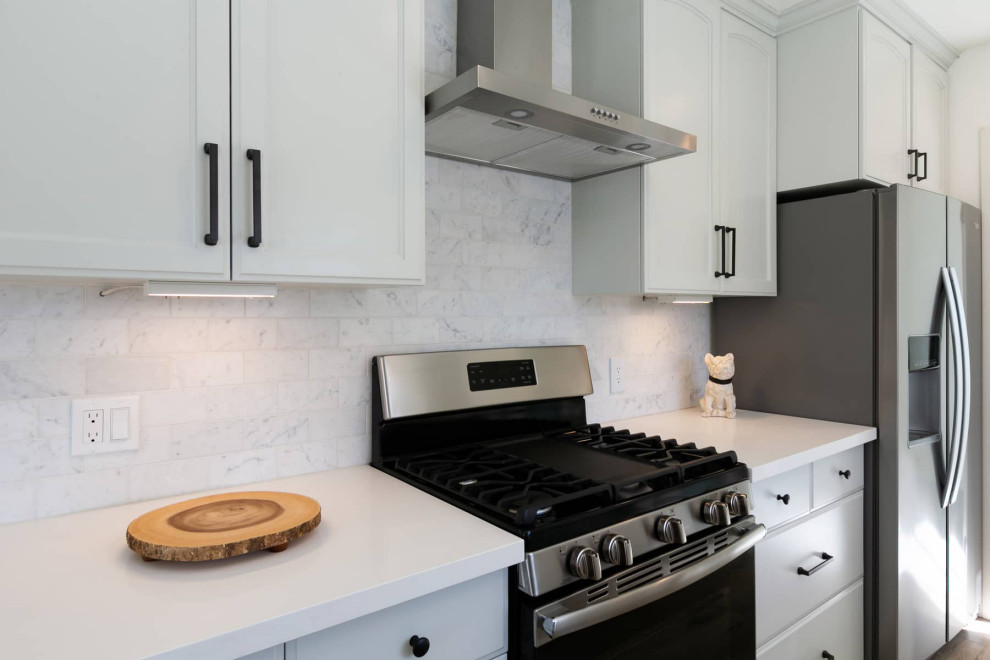 Inspiration pour une petite cuisine américaine parallèle design avec un évier encastré, un placard avec porte à panneau encastré, des portes de placard grises, plan de travail en marbre, une crédence en carrelage métro, un électroménager en acier inoxydable, un sol en bois brun, une péninsule, un sol marron et un plan de travail blanc.