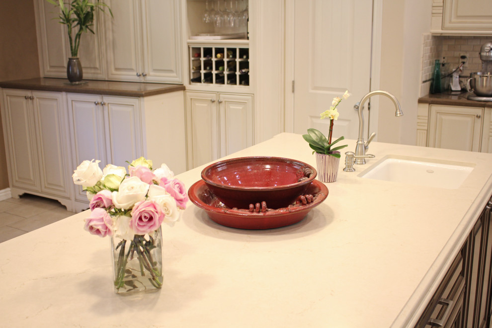 Inredning av ett klassiskt mellanstort flerfärgad flerfärgat kök, med en rustik diskho, luckor med upphöjd panel, vita skåp, bänkskiva i kvartsit, beige stänkskydd, stänkskydd i marmor, rostfria vitvaror, klinkergolv i porslin, en köksö och beiget golv
