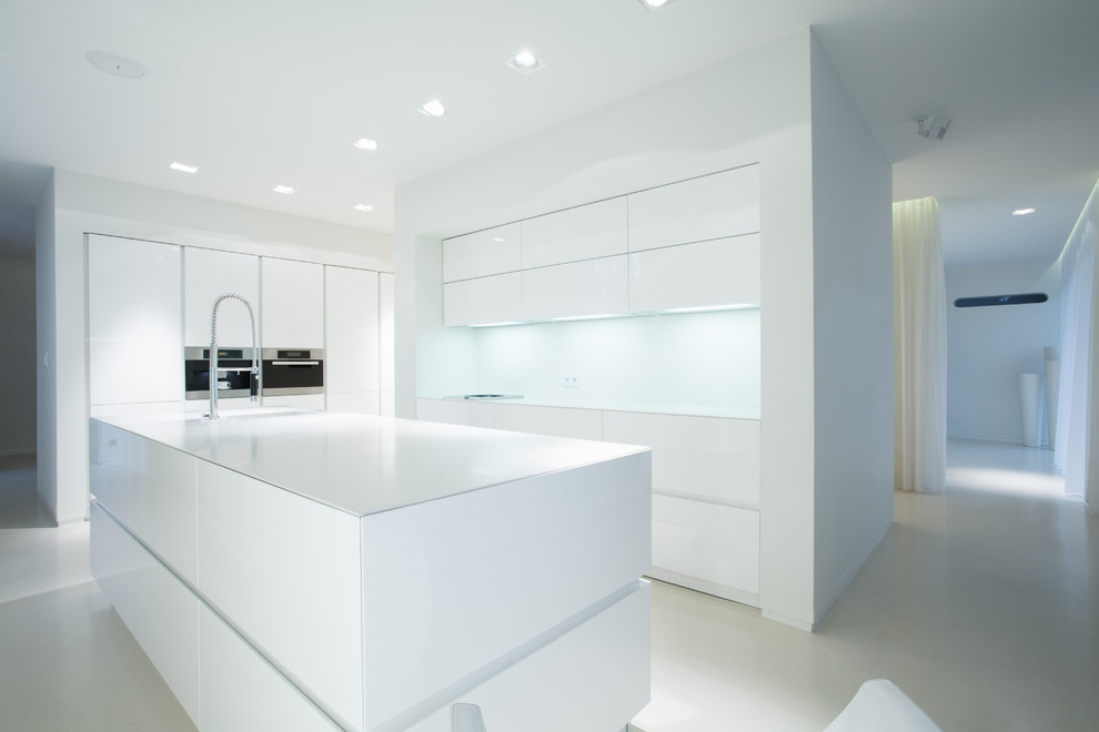 Modelo de cocina comedor moderna con puertas de armario blancas, salpicadero blanco, una isla y encimeras blancas