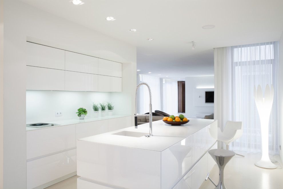 Diseño de cocina comedor moderna con puertas de armario blancas, salpicadero blanco, una isla y encimeras blancas