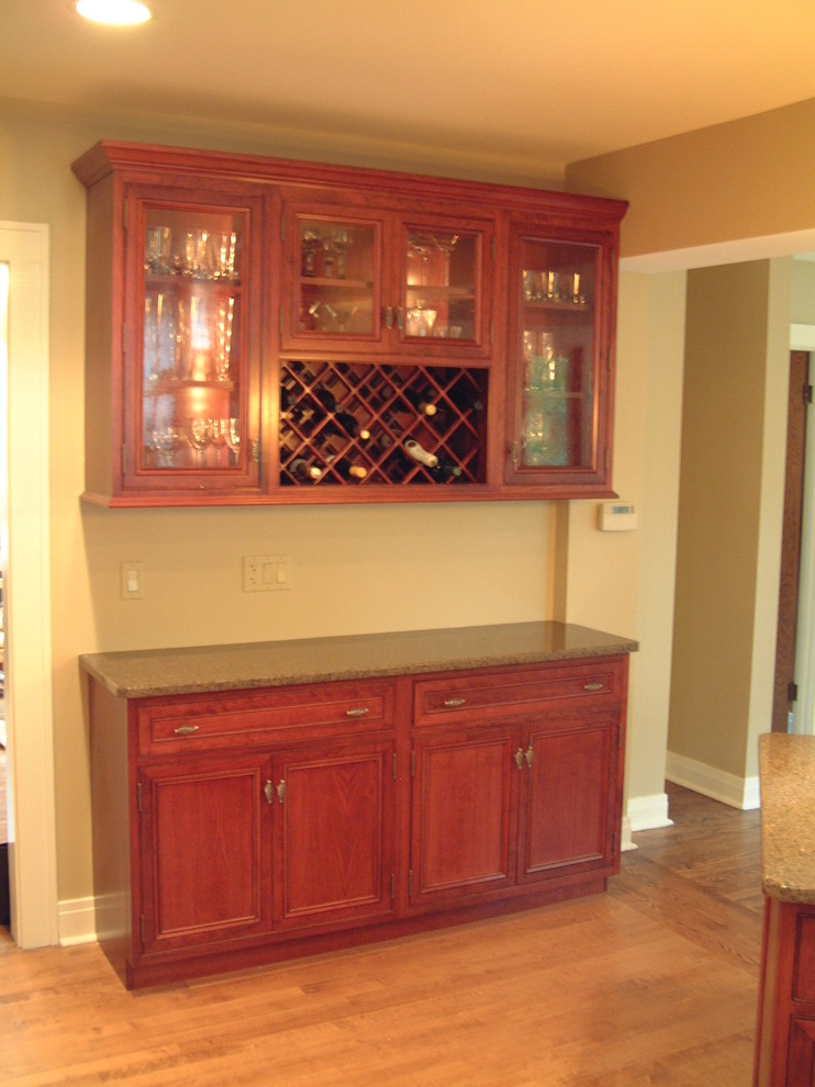 Klassisk inredning av ett mellanstort kök och matrum, med en undermonterad diskho, luckor med upphöjd panel, skåp i mörkt trä, granitbänkskiva, ljust trägolv och flera köksöar