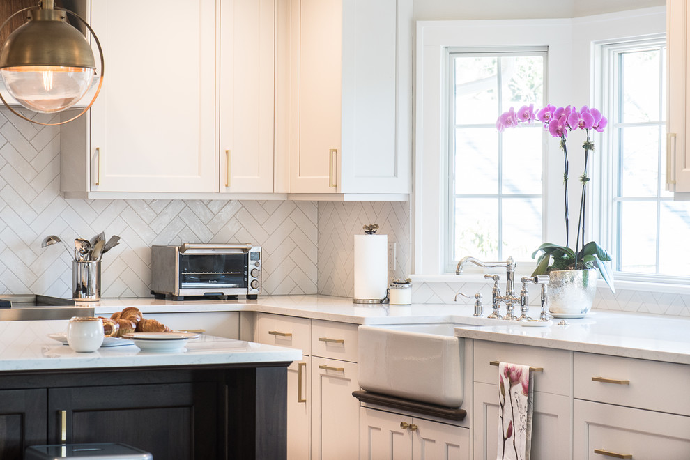 Ejemplo de cocina clásica renovada de tamaño medio con fregadero sobremueble, armarios con paneles lisos, puertas de armario blancas, encimera de cuarzo compacto, salpicadero blanco, salpicadero de azulejos de cerámica, electrodomésticos de acero inoxidable, suelo de madera en tonos medios, una isla, suelo marrón y encimeras blancas