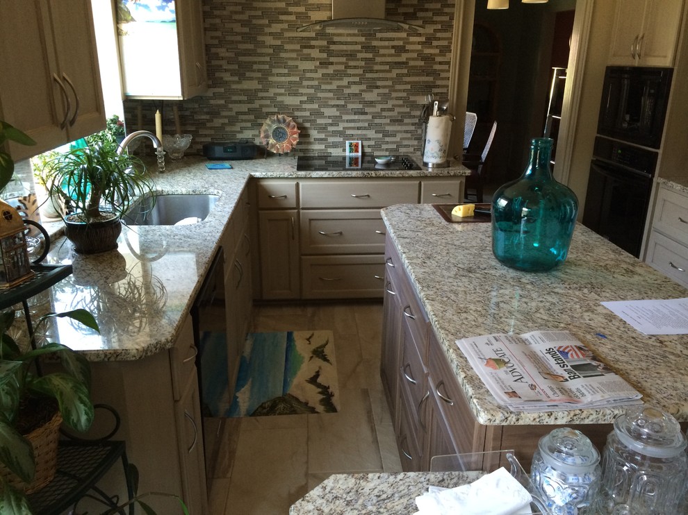 Bild på ett mellanstort funkis kök, med en undermonterad diskho, luckor med infälld panel, vita skåp, granitbänkskiva, rostfria vitvaror och en köksö