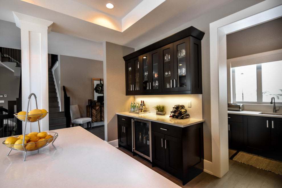 Inspiration for a modern single-wall dry bar in Edmonton with dark wood cabinets, granite worktops, light hardwood flooring, brown floors, white worktops, no sink and shaker cabinets.