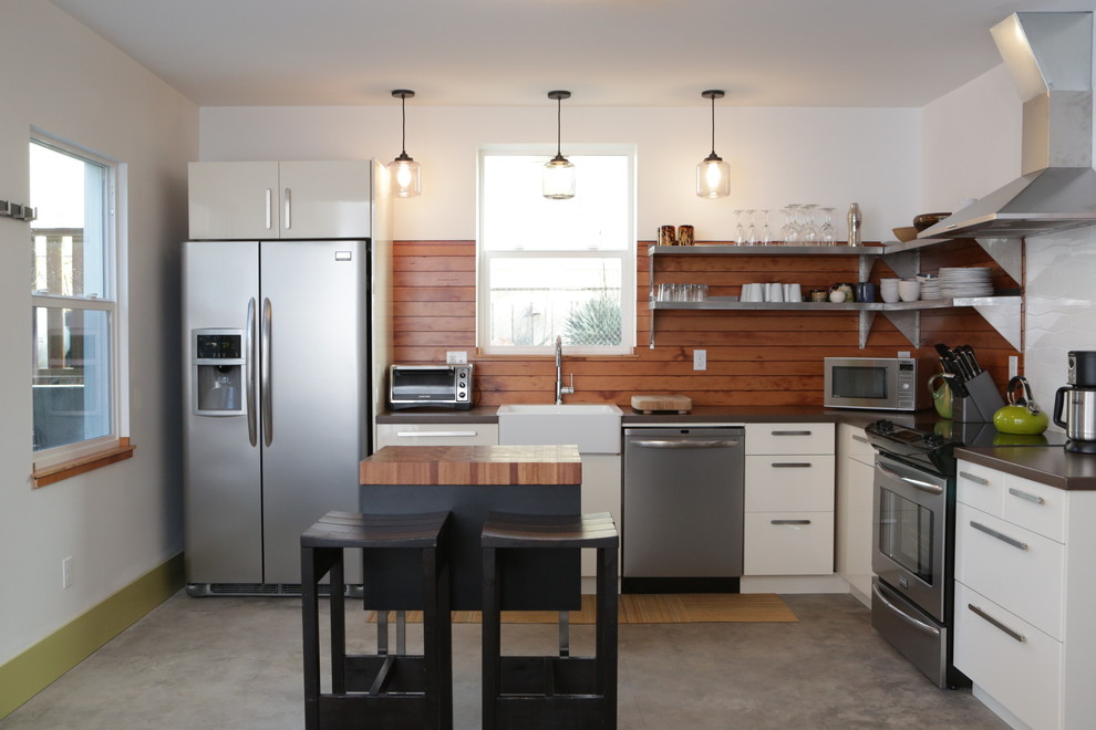 ポートランドにあるコンテンポラリースタイルのおしゃれなL型キッチン (フラットパネル扉のキャビネット、シルバーの調理設備、エプロンフロントシンク、コンクリートカウンター) の写真