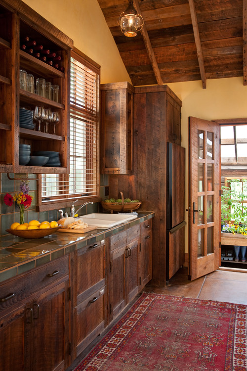 Rustic farmhouse kitchen with Eco-Friendly Kitchen Cabinets made from reclaimed wood, tile countertops, and open shelving for glassware