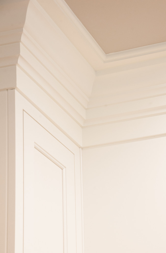 Klassisk inredning av ett kök, med vita skåp, luckor med profilerade fronter, marmorbänkskiva, vitt stänkskydd, stänkskydd i marmor och rostfria vitvaror