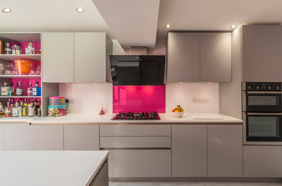 Esempio di un grande cucina con isola centrale design chiuso con ante lisce, ante grigie, top in granito, paraspruzzi rosa, paraspruzzi con lastra di vetro, elettrodomestici in acciaio inossidabile e pavimento in vinile
