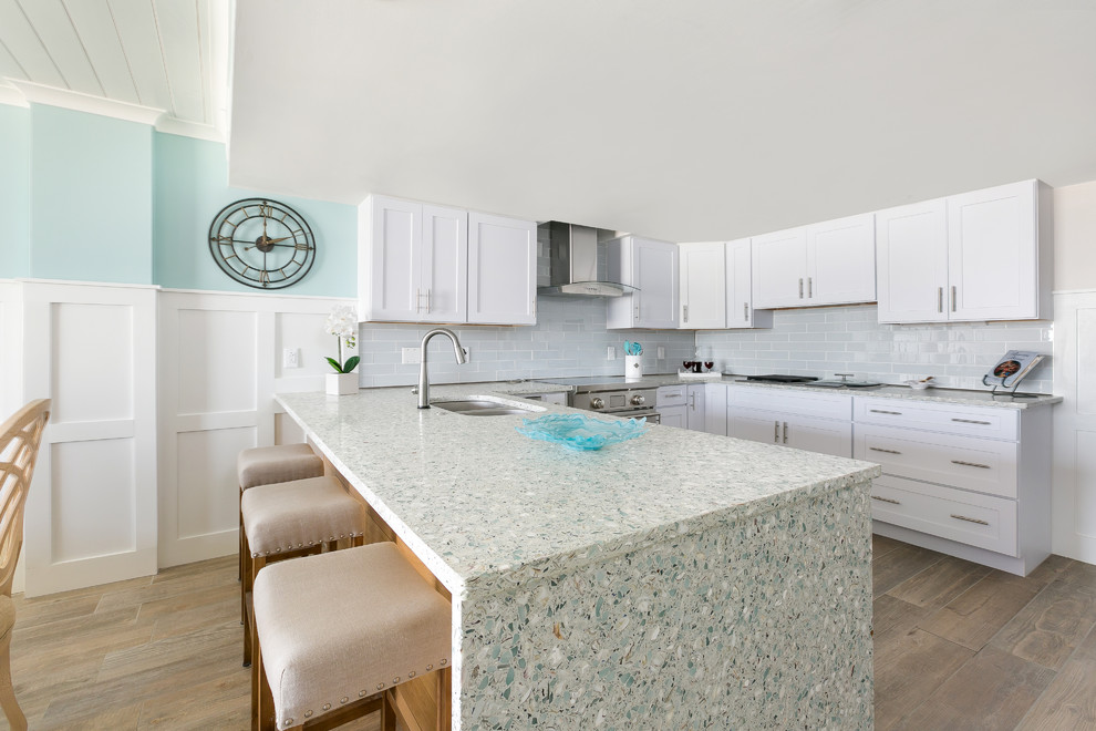 Large nautical u-shaped open plan kitchen in Charleston with a submerged sink, raised-panel cabinets, white cabinets, recycled glass countertops, white splashback, metro tiled splashback, stainless steel appliances, laminate floors, a breakfast bar and multicoloured worktops.