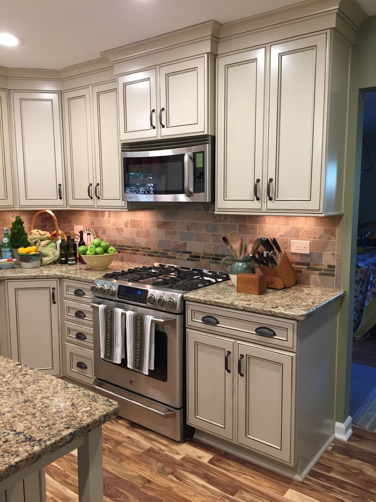 Exempel på ett avskilt, mellanstort amerikanskt l-kök, med en undermonterad diskho, luckor med infälld panel, beige skåp, bänkskiva i kvarts, flerfärgad stänkskydd, stänkskydd i tunnelbanekakel, rostfria vitvaror, mellanmörkt trägolv och en köksö