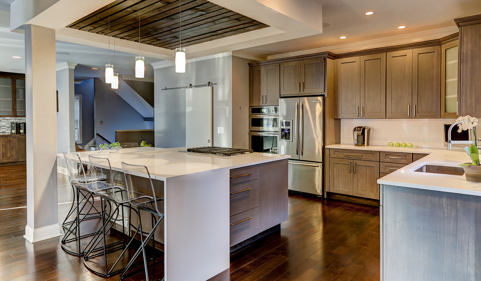 Example of a transitional dark wood floor kitchen design in Other with an undermount sink, gray cabinets, quartzite countertops, white backsplash, porcelain backsplash, stainless steel appliances and an island