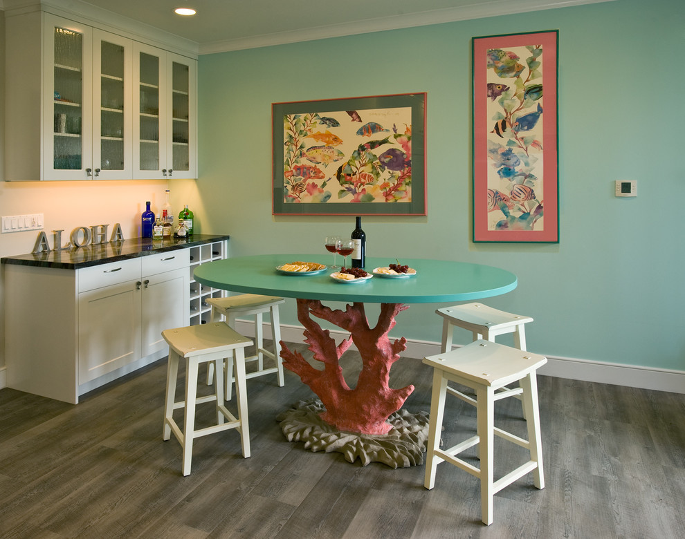Bild på ett tropiskt kök, med luckor med glaspanel, vita skåp, granitbänkskiva, vinylgolv och en köksö