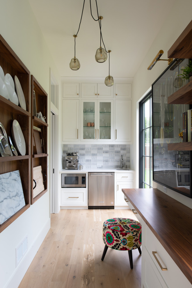 Example of a transitional l-shaped light wood floor and beige floor enclosed kitchen design in Minneapolis with an undermount sink, shaker cabinets, white cabinets, gray backsplash, stainless steel appliances, no island and white countertops