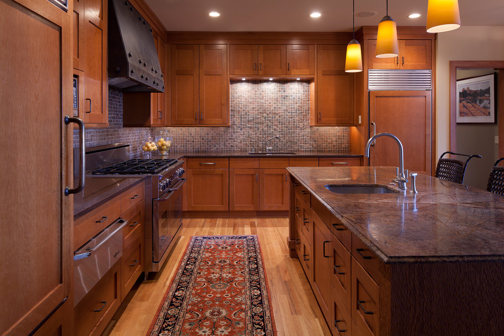 Eat-in kitchen - large craftsman l-shaped light wood floor eat-in kitchen idea in Minneapolis with an undermount sink, recessed-panel cabinets, medium tone wood cabinets, granite countertops, multicolored backsplash, stone tile backsplash, stainless steel appliances and an island