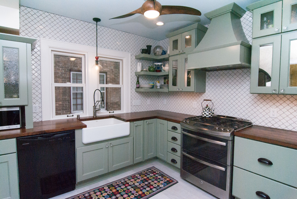 Bild på ett eklektiskt brun brunt l-kök, med en rustik diskho, skåp i shakerstil, gröna skåp, träbänkskiva, vitt stänkskydd, stänkskydd i porslinskakel, rostfria vitvaror, klinkergolv i porslin och grått golv
