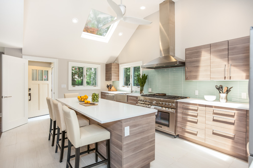 This is an example of a medium sized contemporary l-shaped kitchen in Newark with a belfast sink, flat-panel cabinets, grey cabinets, engineered stone countertops, green splashback, glass tiled splashback, stainless steel appliances, porcelain flooring, an island and white floors.