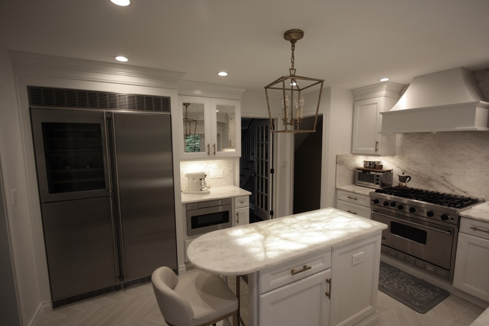 Klassisk inredning av ett mellanstort vit vitt kök, med luckor med infälld panel, vita skåp, bänkskiva i onyx, vitt stänkskydd, stänkskydd i marmor, rostfria vitvaror, klinkergolv i keramik, en köksö och beiget golv