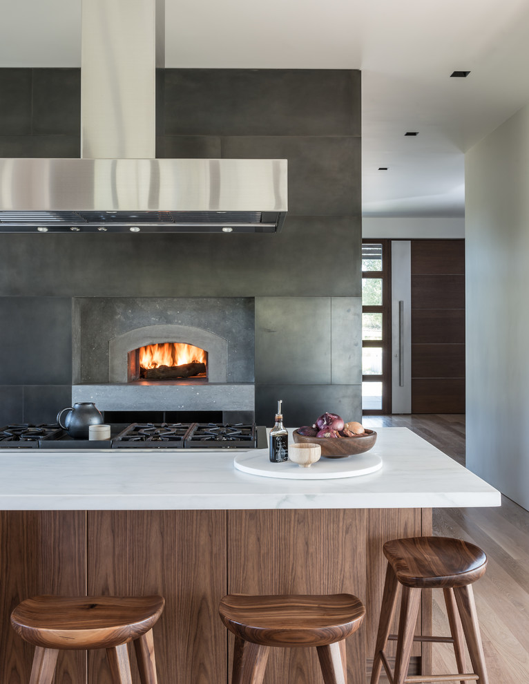 Design ideas for a contemporary kitchen in Salt Lake City with dark wood cabinets, metallic splashback, medium hardwood flooring and an island.