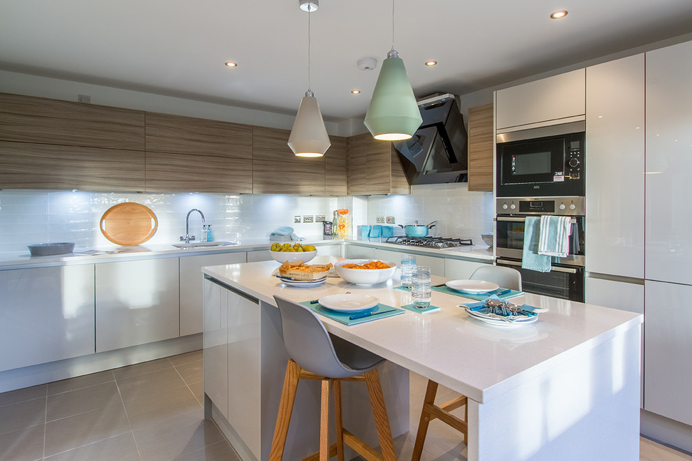 Design ideas for a medium sized contemporary l-shaped kitchen in Gloucestershire with a submerged sink, flat-panel cabinets, white cabinets, white splashback, stainless steel appliances, an island, brown floors and white worktops.