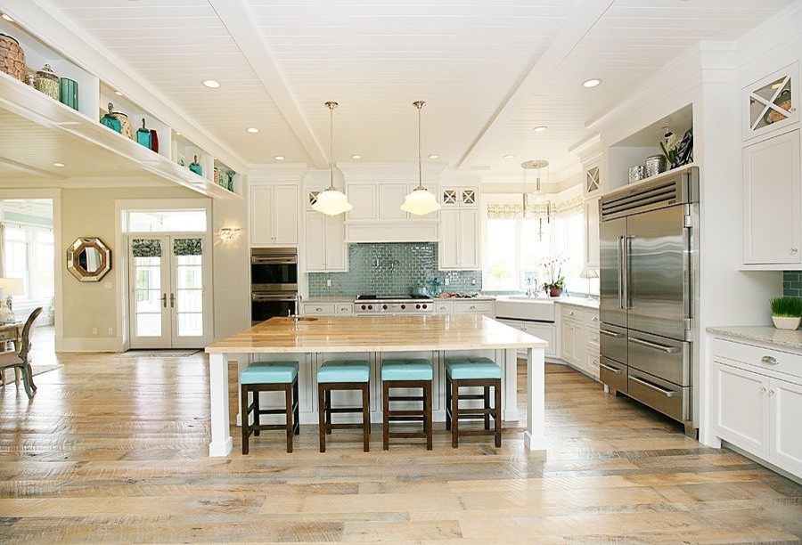 Eclectic kitchen/diner in Salt Lake City with a belfast sink, recessed-panel cabinets, white cabinets, wood worktops, blue splashback, glass tiled splashback, stainless steel appliances, light hardwood flooring and an island.