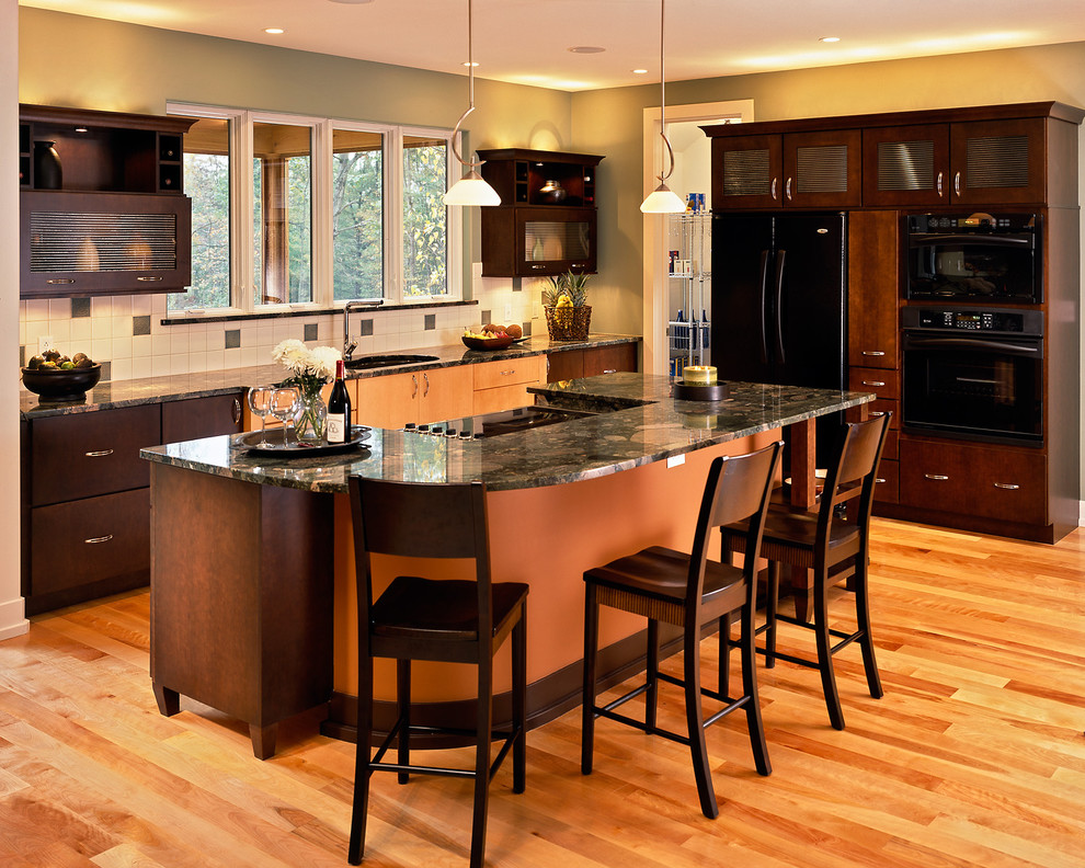 Cette photo montre une cuisine tendance en bois foncé avec un placard à porte vitrée, un électroménager noir et un plan de travail en granite.