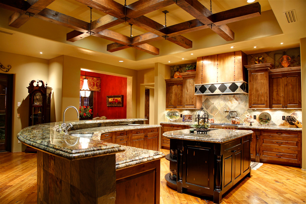 Medelhavsstil inredning av ett stort l-kök, med en undermonterad diskho, luckor med upphöjd panel, skåp i mellenmörkt trä, granitbänkskiva, flerfärgad stänkskydd, stänkskydd i skiffer, mellanmörkt trägolv, flera köksöar och brunt golv