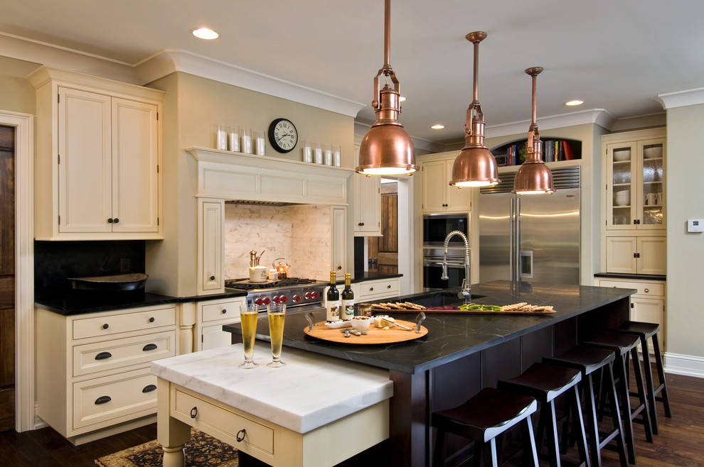 Kitchen - traditional kitchen idea in New York with beaded inset cabinets, stainless steel appliances, soapstone countertops, beige cabinets, white backsplash and stone tile backsplash