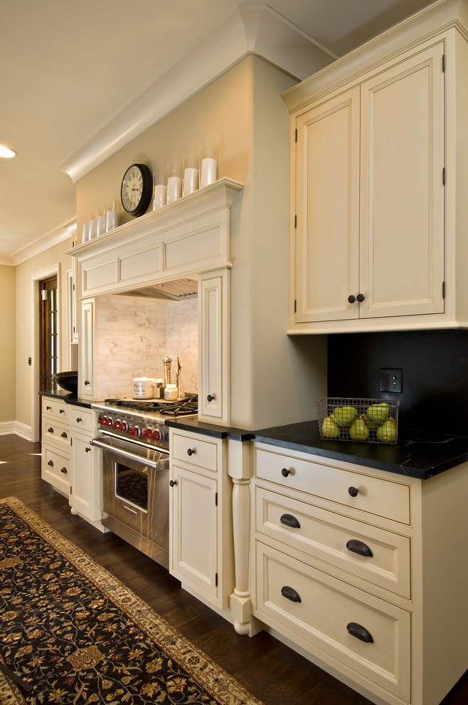 Immagine di una cucina minimalista con ante a filo, ante beige, top in saponaria, paraspruzzi bianco, paraspruzzi con piastrelle in pietra e elettrodomestici in acciaio inossidabile